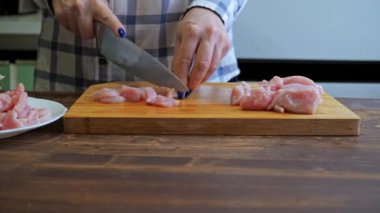 a woman cuts a turkey fillet on a cutting wooden board. cooking in the kitchen. diet food