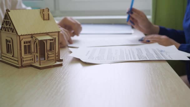 Жінка підписує житловий іпотечний договір. перенесення ключа. на столі є дерев'яний будинок, ключі від майна — стокове відео