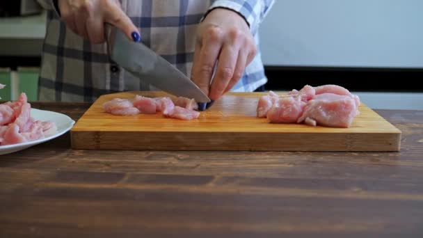 Una mujer corta un filete de pavo en una tabla de madera de corte. cocinar en la cocina. alimentos dietéticos — Vídeo de stock