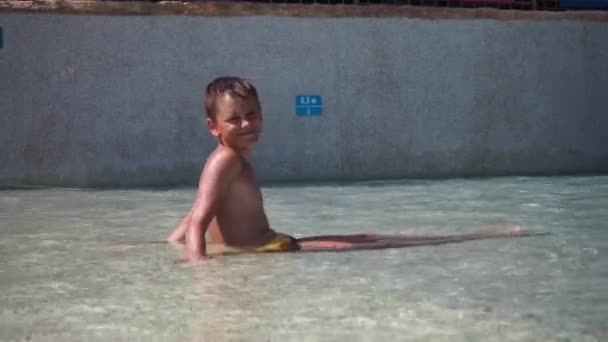 Le onde adolescenti e sorrisi mentre si siede in acqua nella parte bassa della piscina. relax in piscina — Video Stock