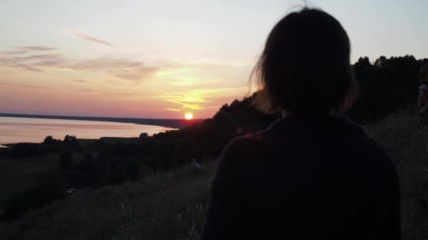 Uma mulher toma um pôr-do-sol no telemóvel. vermelho céu vermelho no fundo. viagens de caminhada. a beleza da natureza — Vídeo de Stock