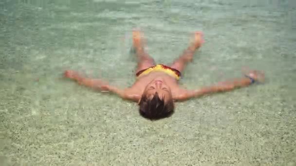 L'adolescente allarga le braccia e le gambe sdraiato nella parte bassa della piscina. un asterisco. relax in piscina — Video Stock