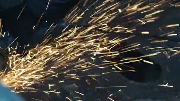 A man in gloves saws metal with a cutting disc. angle grinder. working with metal. fire spray. repair shop. mechanic of mechanical assembly works — Stock Video