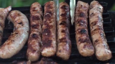 Sosisler ızgarada pişen kömürde kızartılır. Maşayla ters çevir. Lezzetli yemek