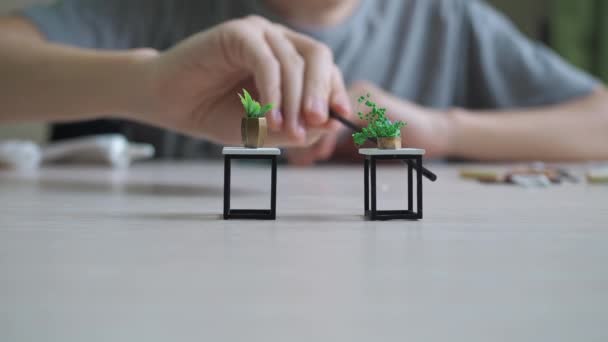 Närbild av pojkarnas händer visar hur han limmade fast bordsmodell. pojken samlar modeller på bordet — Stockvideo