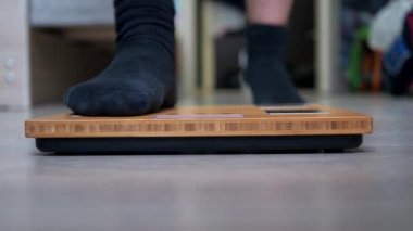 Spor üniformalı bir gencin bacakları terazinin üzerinde duruyor. Libra yakın plan odak noktasında