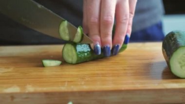 Yakından salatalık dilimliyorum. Kadınların elleri bıçakla sebze keser. Yunan salatasının hazırlanması