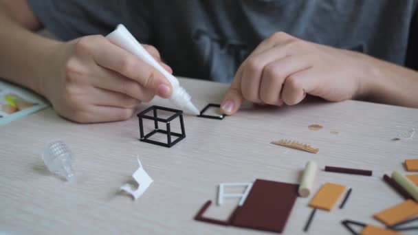 Chlapec přilepí model na stůl. detailní záběr rukou lepících části k sobě — Stock video