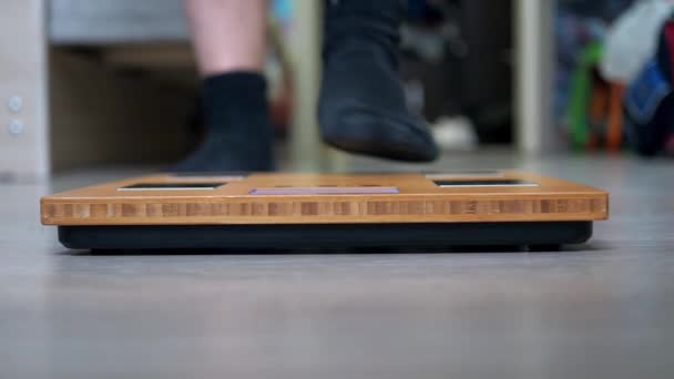 Ноги подростка в спортивной форме стоят на весах. либра крупным планом — стоковое видео