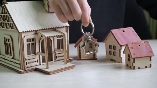 Keychain with apartment keys in hand. toy houses on the table. purchase of real estate. real estate transaction — Stock Video
