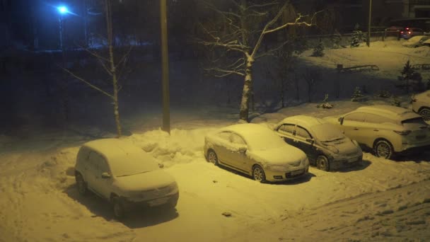 窗外的一场暴风雪，停车场里停着汽车。被路灯照亮了。降雪 — 图库视频影像