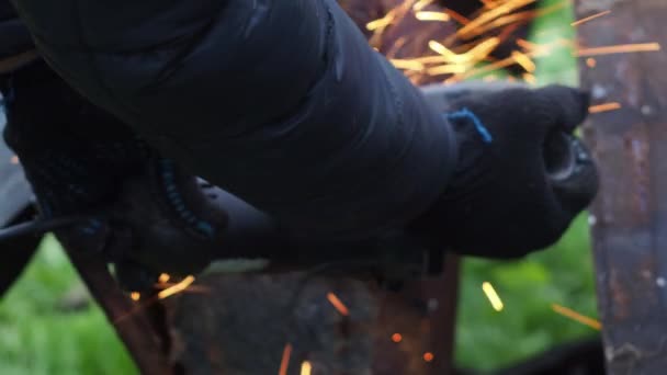 Ein Mann in Handschuhen sägt mit einer Trennscheibe Metall. Winkelschleifer. Arbeiten mit Metall. Feuerspray. Reparaturwerkstatt. Mechaniker für mechanische Montagearbeiten — Stockvideo