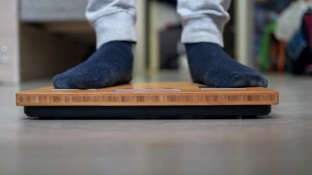 The legs of a teenager in a sports uniform stand on the scales. libra in close-up focus — 图库视频影像