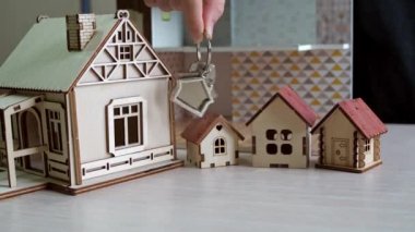 Elinde evin anahtarları olan anahtarlık. Masadaki oyuncak evler. gayrimenkul satın almak. Gayrimenkul işlemi