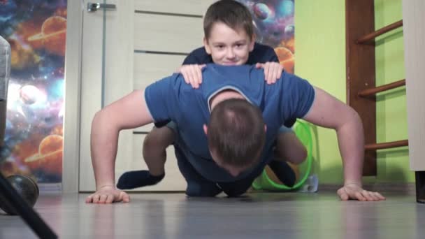 En tonåring på sina fäder tillbaka. Armhävningar från golvet, fitness hemma. idrotta tillsammans — Stockvideo