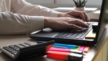 Masaüstü. Erkeklerin elleri bir dizüstü bilgisayarda klavyeye yazıyorlar. Masada bir öğrenci var.