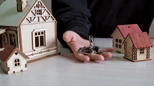 你手上拿着新公寓钥匙的房子形式的钥匙链。购买房地产。新大楼漂亮的钥匙 — 图库视频影像