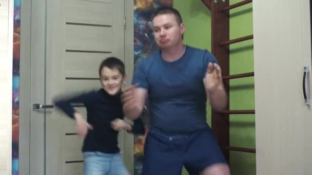 Un giovanotto e suo figlio stanno ballando a casa. divertente ballare. fitness a casa, lezioni con mio figlio — Video Stock