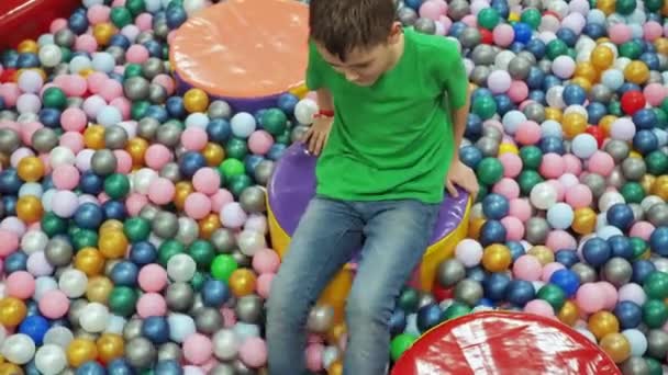 한 소년 이 플라스틱 공을 들고 자기 발로 수영장에서 놀고 있어요. 어린이 연예 센터 — 비디오