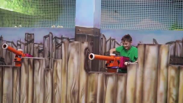 Un chico dispara pelotas desde una ametralladora de juguete. centro de entretenimiento para niños. guerra juego — Vídeos de Stock