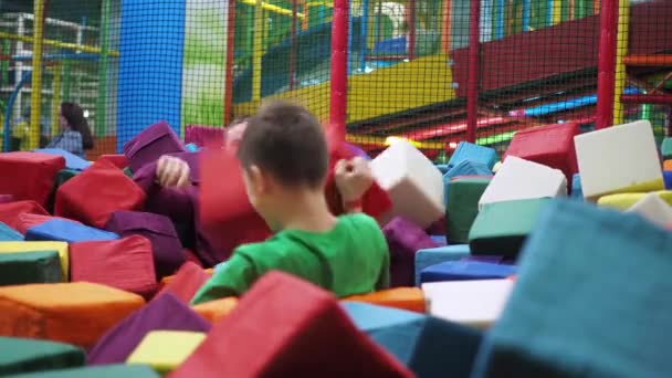 Un adolescente con su padre juega en un charco de cubos suaves. centro de entretenimiento para niños — Vídeos de Stock