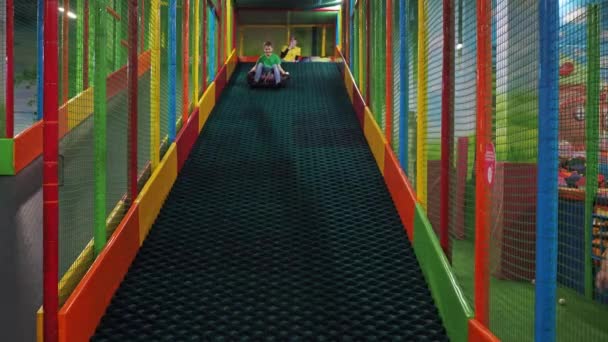 Un adolescente cabalga por un tobogán en un bollo. centro de entretenimiento para niños — Vídeo de stock