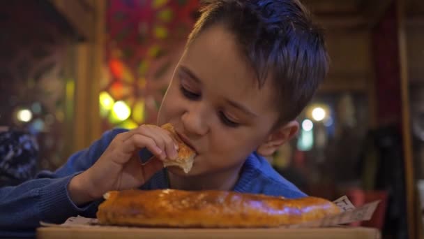 12-летний подросток ест хачапури в Аджарии руками в кафе с удовольствием на лице — стоковое видео