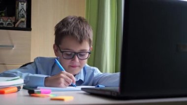 Video kursundan ev ödevi. Bir genç masada oturuyor ve bir deftere yazıyor.