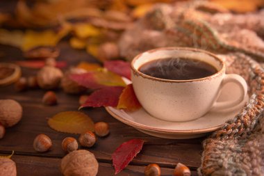 Sonbahar, sonbahar yaprakları, bir fincan sıcak kahve ve ahşap masa arkasında sıcak eşarp. Mevsimlik, sabah kahvesi, pazar dinlendirici ve hayat konsepti..