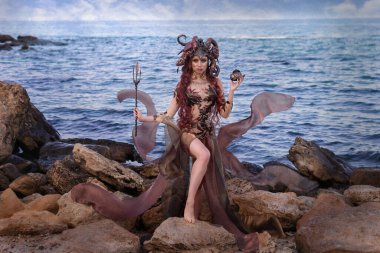beautiful girl sea queen in a dress fluttering in the wind, against the backdrop of the sea
