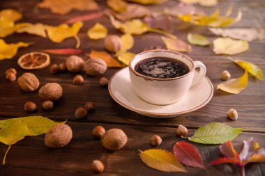 Autumn, autumn leaves, a hot cup of coffee and a warm scarf on a wooden table background. Seasonal, morning coffee, sunday rest and still life concept.