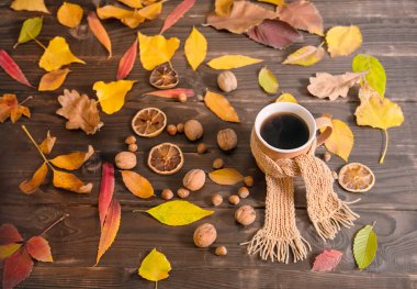 Sonbahar yaprakları, bir fincan sıcak kahve ve ahşap masada sıcak eşarp, üst manzara, fotokopi alanı. Mevsimlik, sabah kahvesi, pazar dinlenmesi, rahatlık ve sıcaklık konsepti..