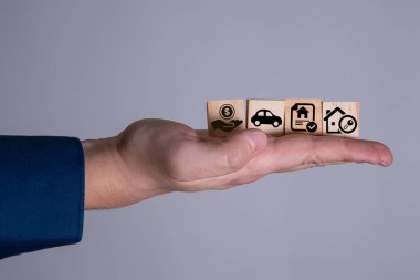 Bir işadamının elinde ahşap küpler ve vergi rozetleri ve mülkü ipotekli bir ev tasviri yapan bir el var. Tarih itibariyle Vergi Mülkiyet Kanunu kavramı.