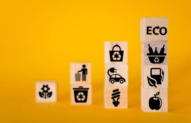 Ahşap küplerdeki simgelerle ekoloji konsepti, sarı arka plan. Tüm dünya için temiz enerji kavramı.