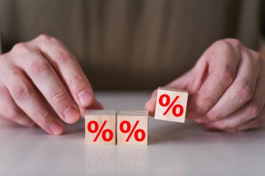 İşadamı ahşap küpün üzerine yüzde ya da yüzde işaretli bir sembol yerleştiriyor. Faiz oranlarının yükseltilmesi veya indirim konsepti.