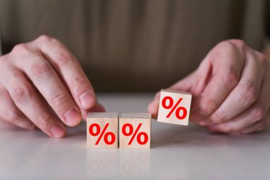 İşadamı ahşap küpün üzerine yüzde ya da yüzde işaretli bir sembol yerleştiriyor. Faiz oranlarının yükseltilmesi veya indirim konsepti.