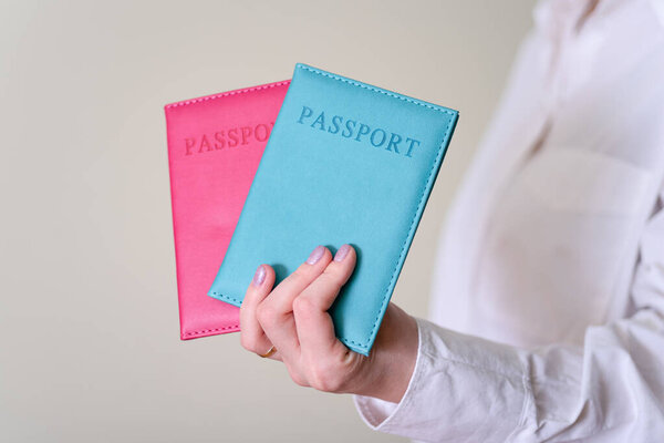 A woman's hand holding two passports on a gray background. The concept of traveling abroad.