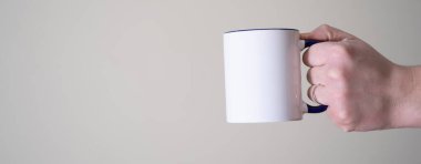 Beyaz kupa arka plandaki bir adamın elinde. Lezzetli ve sıcak kahve veya çay konsepti.