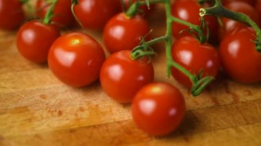 Daldaki kiraz domatesleri kesme tahtasının üzerinde dönüyorlar. Kirazlı sebzelerle sağlıklı beslenme kavramı..