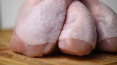 Çiğ, taze tavuk budu, doğrama tahtasında daireler çizerek dönüyor. Tavuk butları şeklinde taze ve diyet mutfağı kavramı..