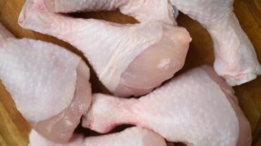 Çiğ, taze tavuk budu, doğrama tahtasında daireler çizerek dönüyor. Tavuk butları şeklinde taze ve diyet mutfağı kavramı..