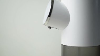 Beyaz arka planda sıvı sabun için sabun makinesi. Otomatik sabunluk kullanıyor. Beyaz köpüklü sabun.