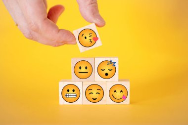 Bir müşterinin eli, tahta bir küpte gözleri yerine kalbi olan gülen bir yüzü seçerken. Dünya gülen gün konsepti.