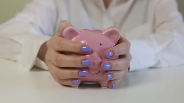Großaufnahme Von Frauenhänden Streicheln Eines Rosafarbenen Sparschweins Auf Einem Holztisch — Stockvideo