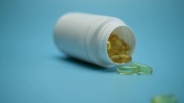 Kavanozdan omega-3 balık yağı sıvı jel kapsülleri dökülüyor. Kişisel bakım, sağlıklı yaşam tarzı..