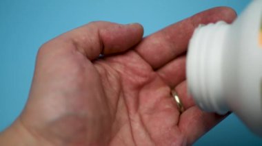 Bir adam eline bir kapsül balık yağı döküyor. Omega 3 'e yakın çekim. Omega 3 Altın balık yağı kapsülleri.