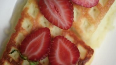 Masada dönen çilekli Belçika waffleları. Lezzetli bir kahvaltı konsepti.