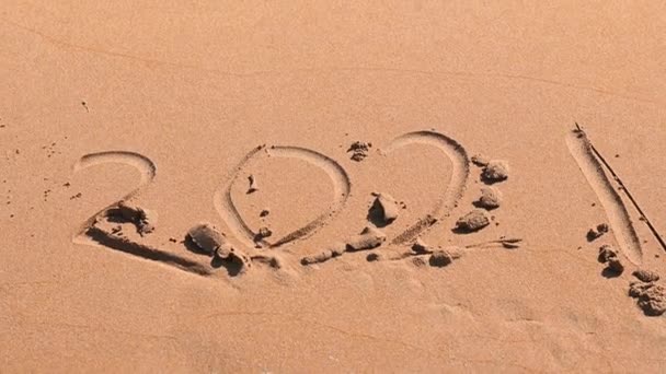 Море на песке на пляже смывает номера 2021 как концепция уходящего года — стоковое видео