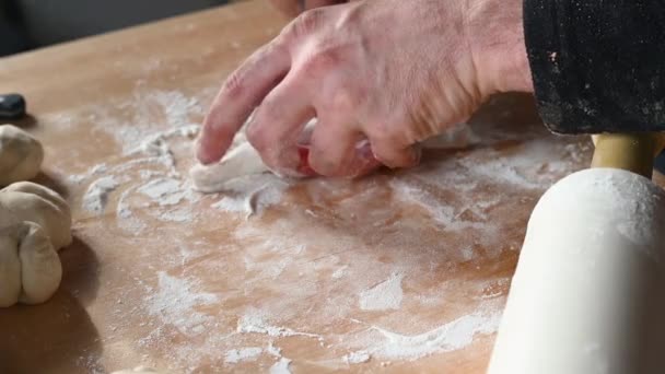 Mężczyzna w kuchni w domu przygotowuje pastie na stole, wywala ciasto, wkłada mielone mięso do domu — Wideo stockowe