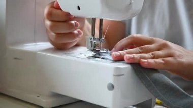 Terzi kadın dikiş makinesine kadın eli diker.